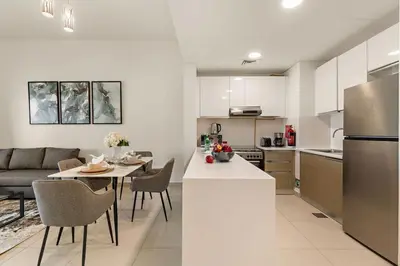 a kitchen and living room with a table and a refrigerator at The Smart Concierge - Andalus Jumeirah Golf Estates in Dubai