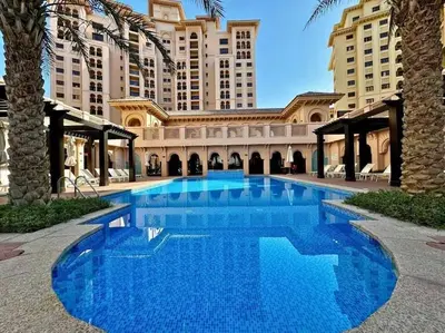 a large blue swimming pool in front of a building at The Smart Concierge - Andalus Jumeirah Golf Estates in Dubai