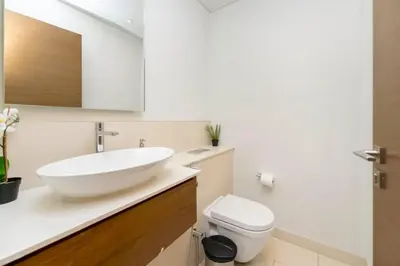 a bathroom with a white sink and a toilet at Stylish 2BR with Maids Room City Walk in Dubai