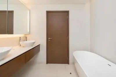 a bathroom with two sinks and a wooden door at Stylish 2BR with Maids Room City Walk in Dubai