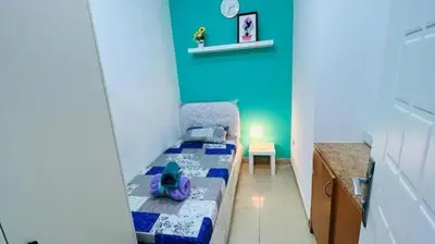 a small bedroom with a bed and a blue wall at Budget Stay Dubai Tecom Barsha Heights in Dubai