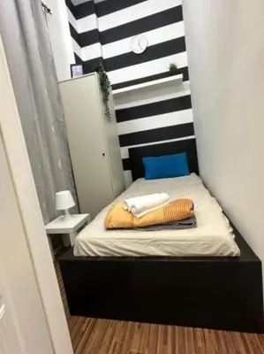 a small bed in a room with a striped wall at Budget Stay Dubai Tecom Barsha Heights in Dubai