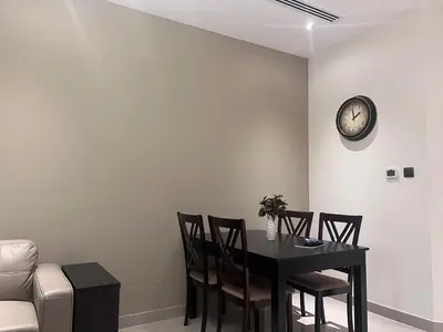 a dining room table with chairs and a clock on the wall at Elite Residence 1, Downtown Dubai in Dubai