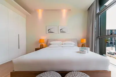 a large white bed in a room with a large window at Spacious 2BR with Maids Room City Walk in Dubai