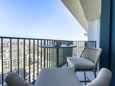 a balcony with two chairs and a table with a view at Superhost - 1BR Apartment, Balcony, Pool & Gym , Dubai Hills in Dubai