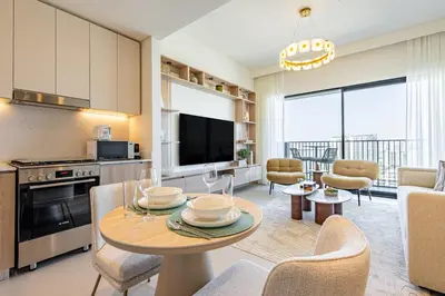 a kitchen and living room with a table and chairs at Superhost - 1BR Apartment, Balcony, Pool & Gym , Dubai Hills in Dubai