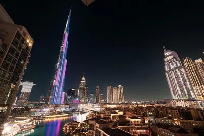 a view of a city at night with lit up buildings at Large 4 Bed Apt with Burj View and 8 Min Walk to Mall by Vista Stays DXB in Dubai