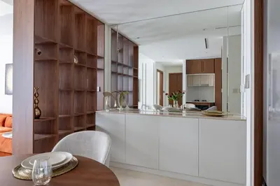 a kitchen with white cabinets and a wooden wall at Luxury & Modern Unit in Emaar Beachfront in Dubai
