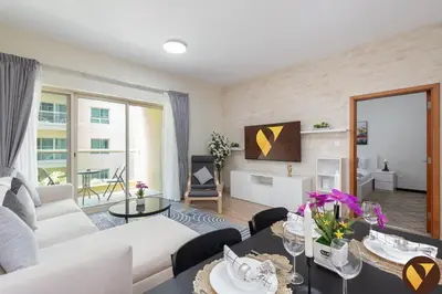 a living room with a white couch and a table at Vogue The Greens Al Alka near Mall of the Emirates, One Bedroom Apartment with Balcony and Vibrant community View, Access to all Amenities in Dubai