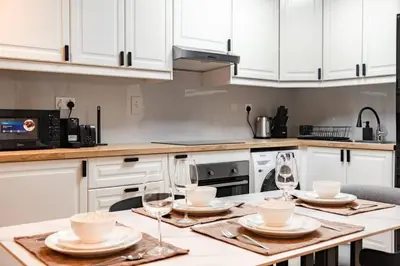 a kitchen with white cabinets and a table with wine glasses at Sulafa Tower, Dubai Marina - Onelink in Dubai