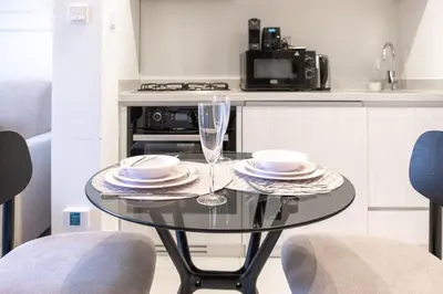 a glass table with two plates and a wine glass at Zada Tower, Business Bay - Onelink in Dubai