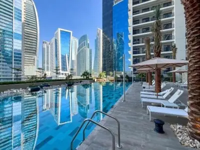 a swimming pool with chairs and an umbrella and a city at Zada Tower, Business Bay - Onelink in Dubai