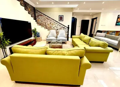 a living room with yellow couches and a flat screen tv at Risephoenix Japanese Luxury Capsule Villa - Dubai in Dubai