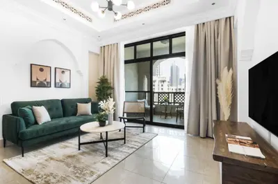 a living room with a green couch and a tv at Silkhaus in Al Tajer in Souk al Bahar Direct Access in Dubai