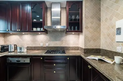 a kitchen with wooden cabinets and a stove top oven at Silkhaus in Al Tajer in Souk al Bahar Direct Access in Dubai
