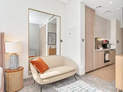 a living room with a chair and a mirror at Peninsula One Suites by Prestige Nest in Dubai