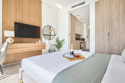 a bedroom with a bed and a flat screen tv at Frank Porter - Peninsula One in Dubai