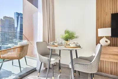 a dining room with a table and chairs and a window at Frank Porter - Peninsula One in Dubai