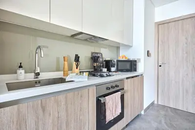 a kitchen with a sink and a stove top oven at Frank Porter - Peninsula One in Dubai