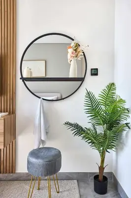 a round mirror and a stool in a room with a plant at Frank Porter - Peninsula One in Dubai