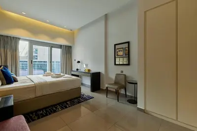 a bedroom with a bed and a desk and a chair at Majesty Stay 2BR in Dubai