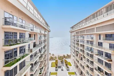 two tall buildings with the ocean in the background at The Iconic Stay 2BR in Dubai