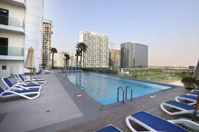 a large swimming pool with lounge chairs and buildings at Velvet Rose with Burj and canal view 2Bedrooms in Solbay in Dubai