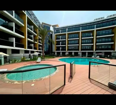 a large building with a swimming pool in front of a building at Refined Urban Studio Walk to Circle Mall in Dubai