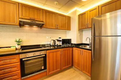 a kitchen with wooden cabinets and a stainless steel refrigerator at Barsana - Aurelia by JBR Beach - 2 Bed - Marina Views! in Dubai