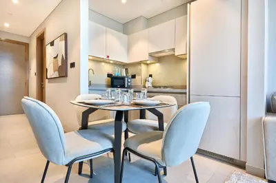 a dining room with a table and chairs and a kitchen at STAY BY LATINEM Luxury 1BR Holiday Home W-407 near Burj-Khalifa in Dubai