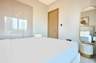 a bedroom with a large white bed and a mirror at STAY BY LATINEM Luxury 1BR Holiday Home W-407 near Burj-Khalifa in Dubai