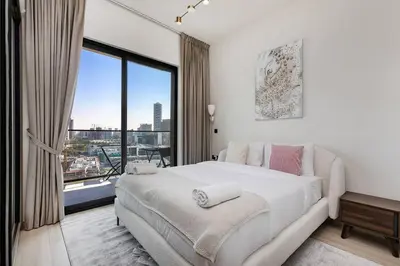 a bedroom with a large white bed and a large window at Elegant 2BR Apartment in Binghatti Heights in Dubai
