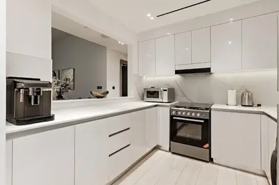 a white kitchen with white cabinets and appliances at Elegant 2BR Apartment in Binghatti Heights in Dubai