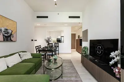 a living room with a green couch and a table at Elegant 2BR Apartment in Binghatti Heights in Dubai