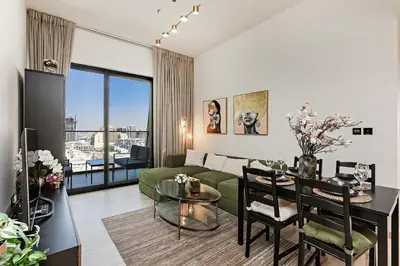 a living room with a green couch and a table at Elegant 2BR Apartment in Binghatti Heights in Dubai
