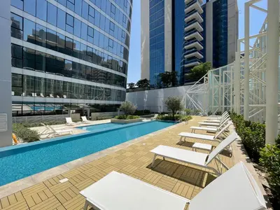 a swimming pool with lounge chairs and buildings at Modern 1BR with Stunning Lake View in Business Bay in Dubai