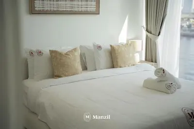 a white bed with towels on it with a window at Modern 1BR with Stunning Lake View in Business Bay in Dubai