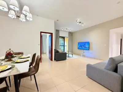 a dining room and living room with a table and chairs at Brand-New 4BR on JBR Beach Near metro, mall By Sunkissed Holiday Homes in Dubai