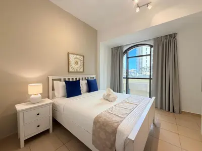 a bedroom with a large bed and a window at Brand-New 4BR on JBR Beach Near metro, mall By Sunkissed Holiday Homes in Dubai