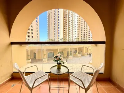 a room with a table and chairs and a window at Brand-New 4BR on JBR Beach Near metro, mall By Sunkissed Holiday Homes in Dubai