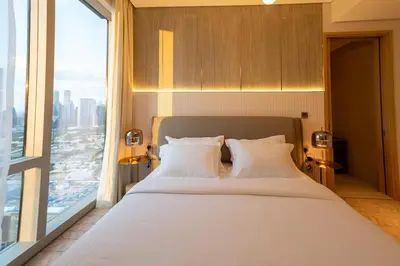 a bedroom with a white bed with a large window at Stylish 2BR Connected to Dubai Mall with Full Burj Khalifa View in Dubai