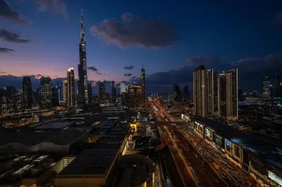 a city skyline at night with a train station at Stylish 2BR Connected to Dubai Mall with Full Burj Khalifa View in Dubai