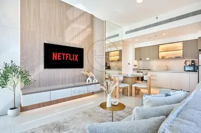a kitchen and living room with a netflix sign on the wall at Elegant beachfront living at Emaar Beachfront DXB! in Dubai