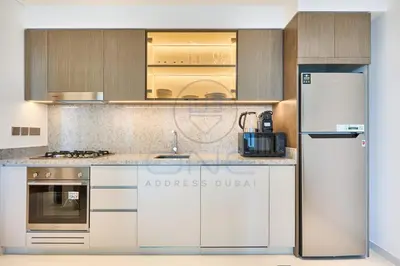 a kitchen with white cabinets and a refrigerator at Elegant beachfront living at Emaar Beachfront DXB! in Dubai