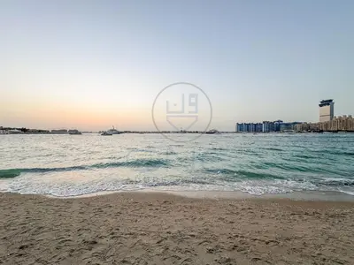 a view of the beach with a boat in the water at Elegant beachfront living at Emaar Beachfront DXB! in Dubai