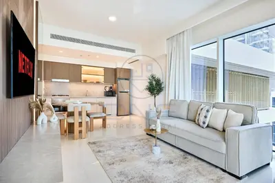 a living room with a couch and a kitchen at Elegant beachfront living at Emaar Beachfront DXB! in Dubai