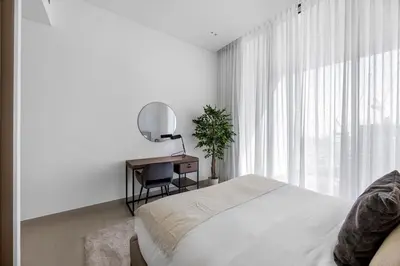 a bedroom with a bed and a desk and a mirror at Chic 1BR Retreat with Private Pool and Balcony in JVC in Dubai