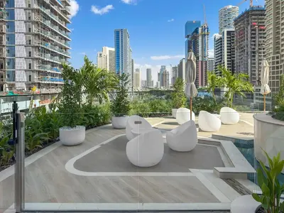 a rooftop patio with white chairs and a city skyline at Chic 1BR Retreat with Private Pool and Balcony in JVC in Dubai