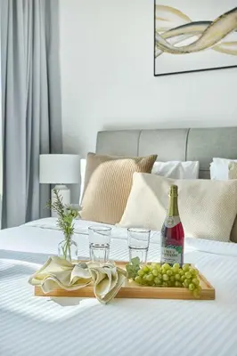 a tray of grapes and a bottle of wine on a bed at Frank Porter - Al Majara, Dubai Marina in Dubai