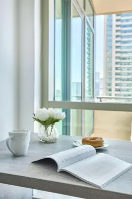 a table with a book and a vase of flowers and a donut at Frank Porter - Al Majara, Dubai Marina in Dubai